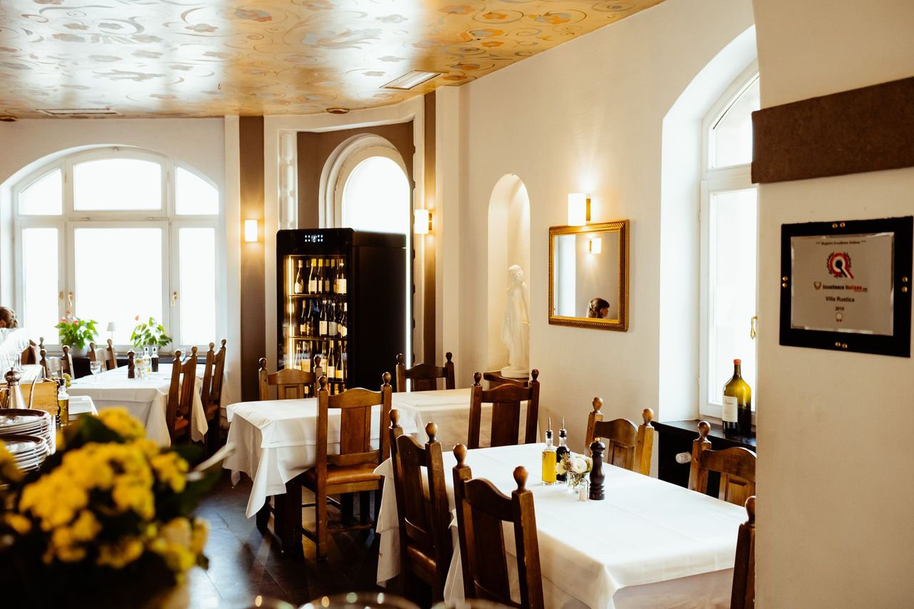 Heller Innenraum des Restaurants Villa Rustica in Stuttgart mit mehreren Tischen, die mit weißen Tischdecken, Essig und Öl sowie Salz und Pfeffer eingedeckt sind 